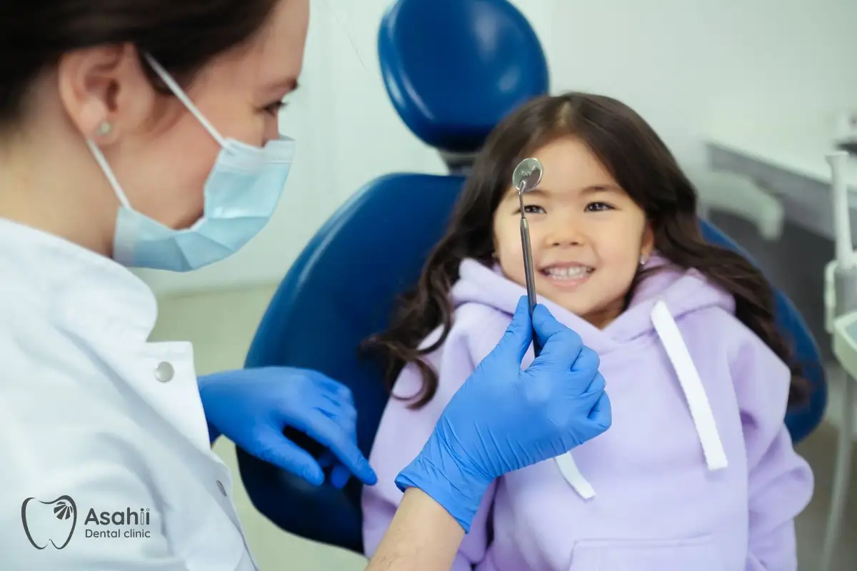 The dentist lets a child play with the dental mirror so she isn't afraid of check-ups