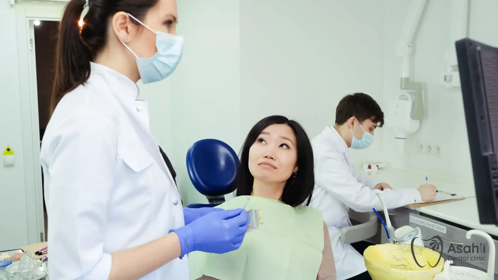 The dentist uses a shade guide to match the colour of a crown to the patient's teeth