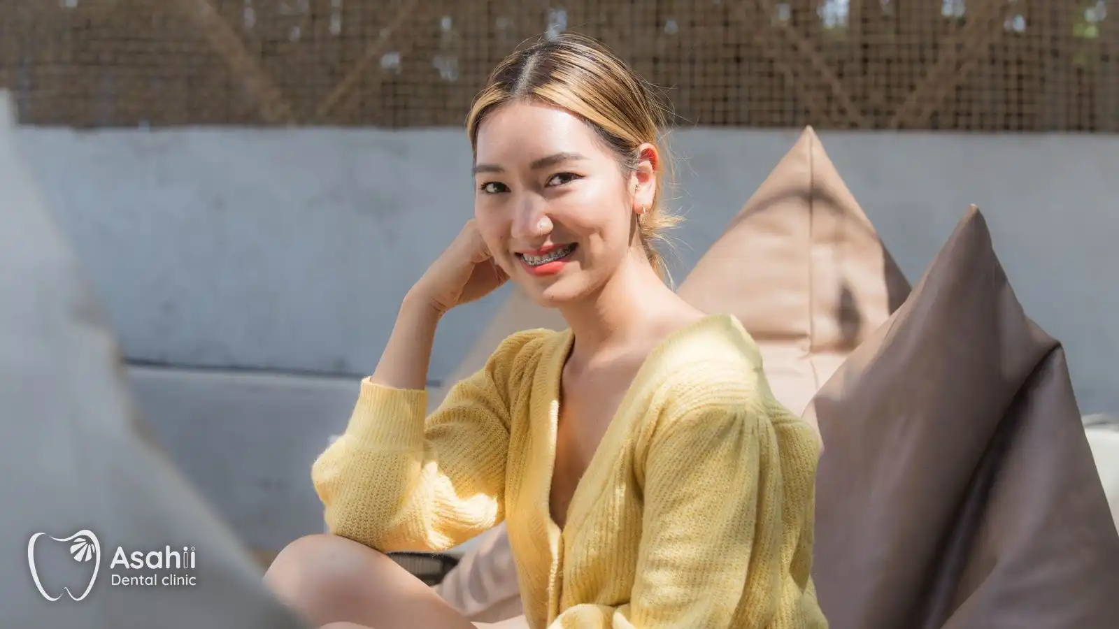A smiling young woman in metal braces: eating well and cleaning properly keep orthodontic treatment on track