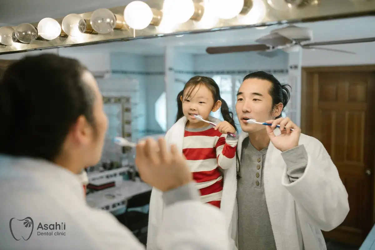 A father brushing his teeth with his daughter: good home habits are the best protection for baby teeth