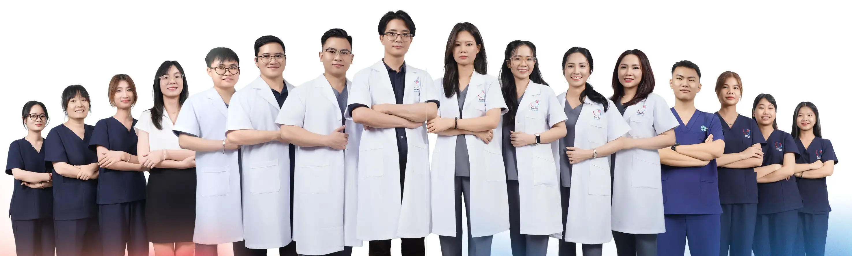 Toàn thể đội ngũ Nha Khoa Asahii – bác sĩ trong áo blouse trắng, trợ thủ và lễ tân trong đồng phục xanh – khoanh tay đứng cạnh nhau